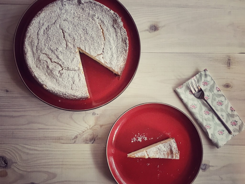 cały sernik i odkrojony kawałek na czerwonych talerzach